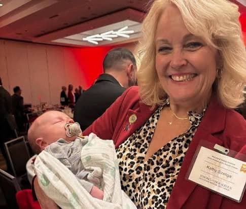 Kathy Szeliga smiling as she holds a sleeping newborn baby.