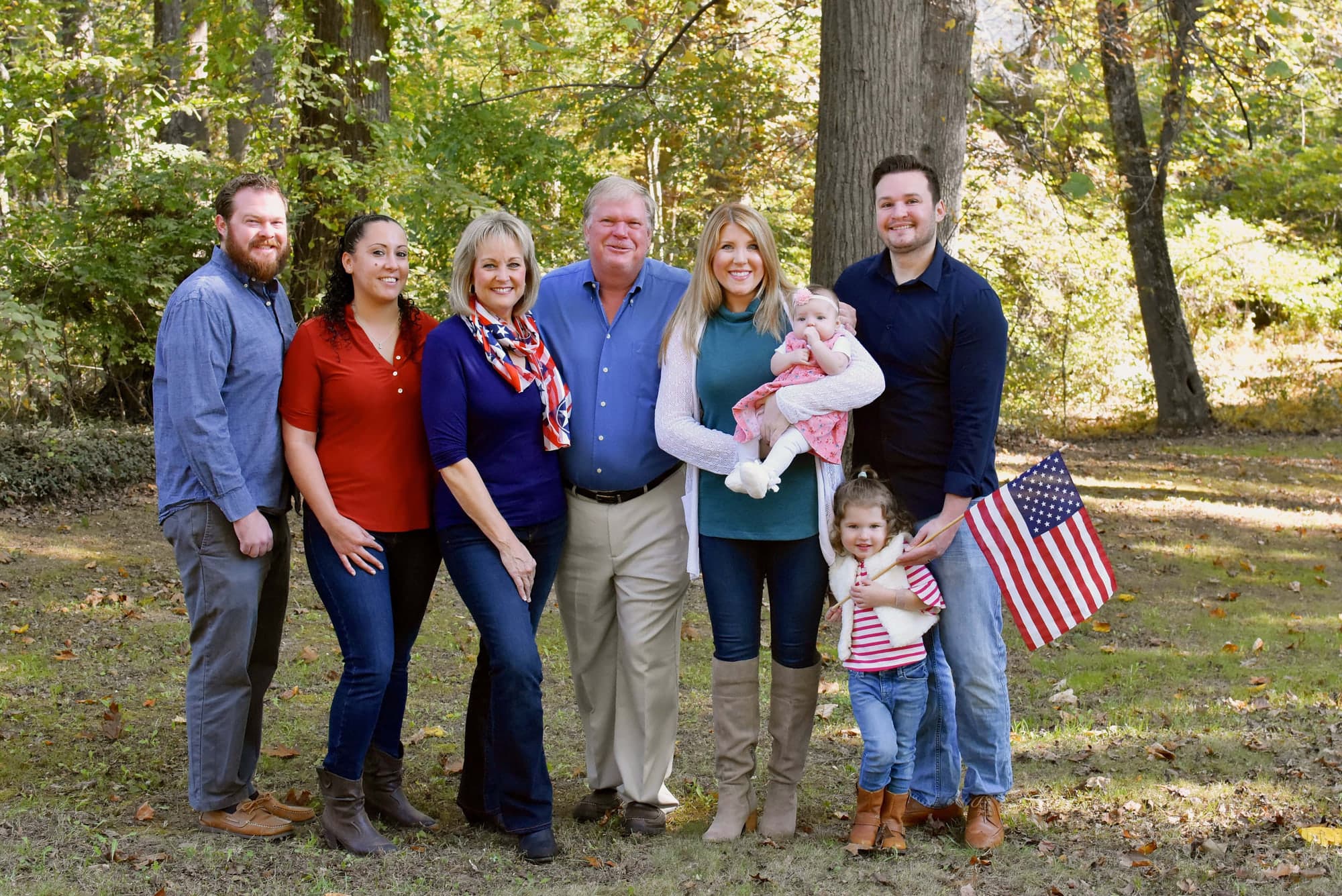 The Szeliga family outdoors in autumn, a granddaughter holding an American flag.