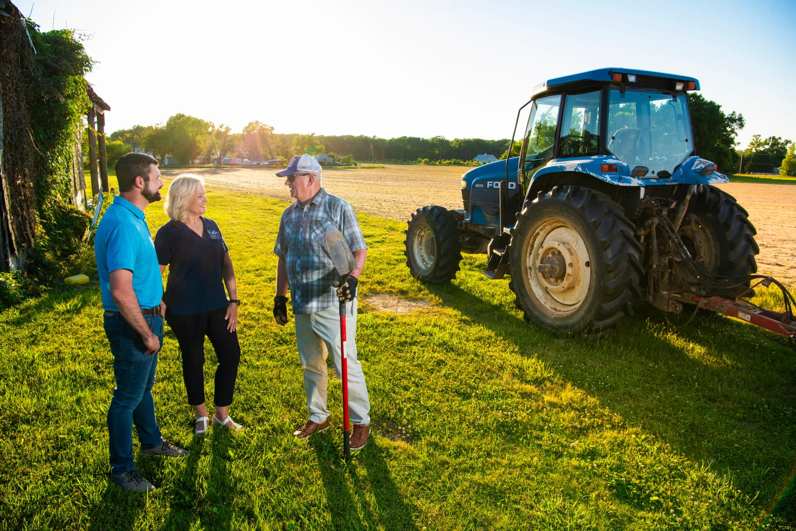 Kathy Szeliga talking with farmers beside a tractor on a District 7A farm at golden hour.
